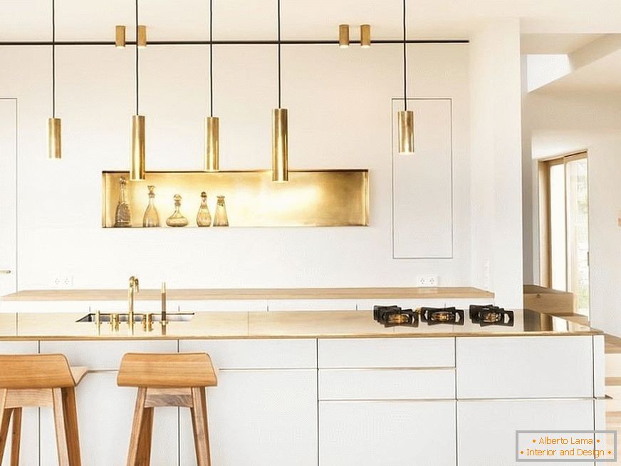Arany dekor elemek egy fehér konyhában, fából készült bárszékekkel