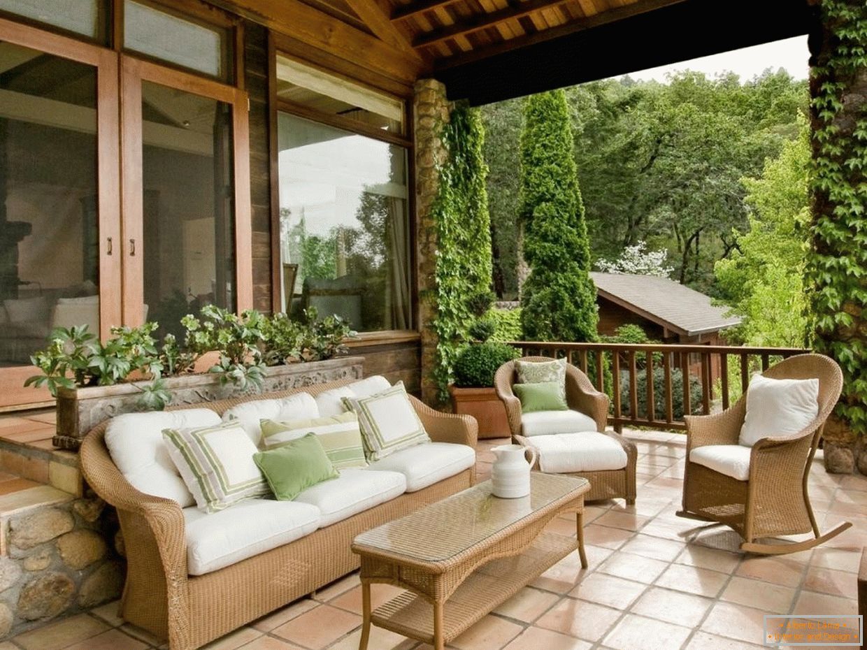 A verandán fehér párnával ellátott fából készült bútorok