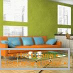Narancsszínű kanapé kék párnákkal a pisztácia falán
