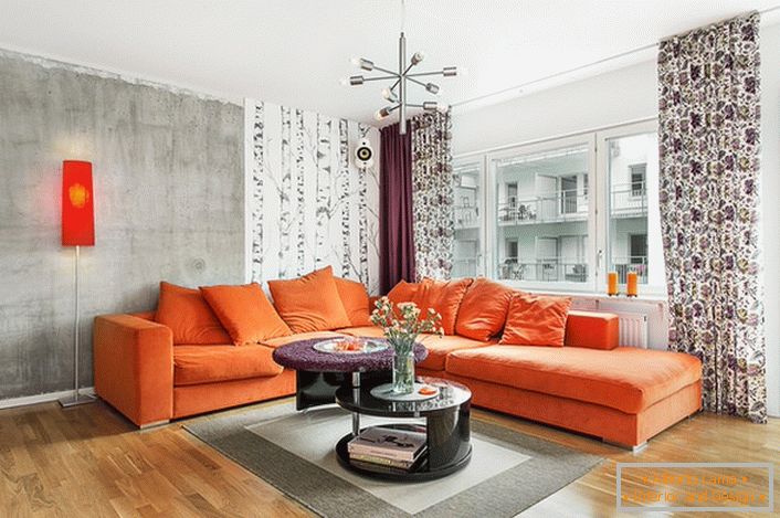 A skandináv stílus beleszámít a meleg színek használatába a belsőépítészetben. A puha narancssárga kanapé organikusan a hideg szürke színárnyalat hátterében néz.