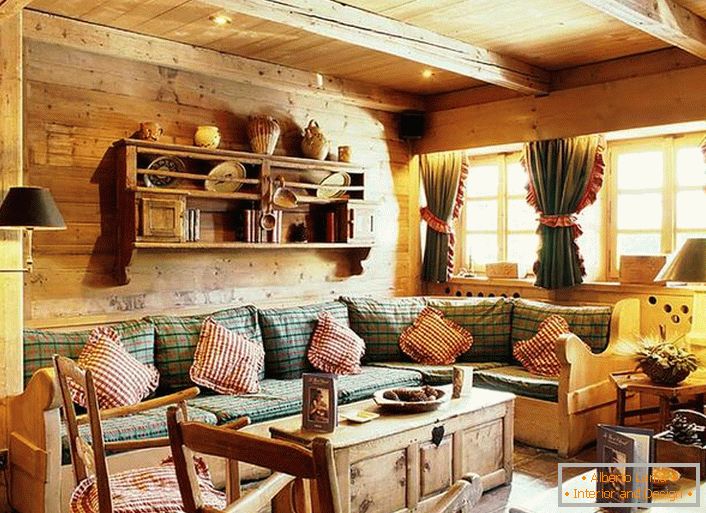 Fa fali dekoráció, párnázott párnák egy puha kanapén, sűrű függönyök fodrosokkal az ablakokon. Hangulatos nappali rusztikus stílusban egy vidéki házban.