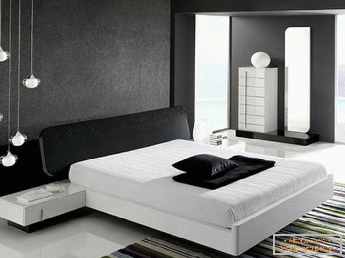 Az ágy fején, a szürke matt betéttel díszített fal a hi-tech stílusnak megfelelően összhangban van a fényes fehér padlóval.
