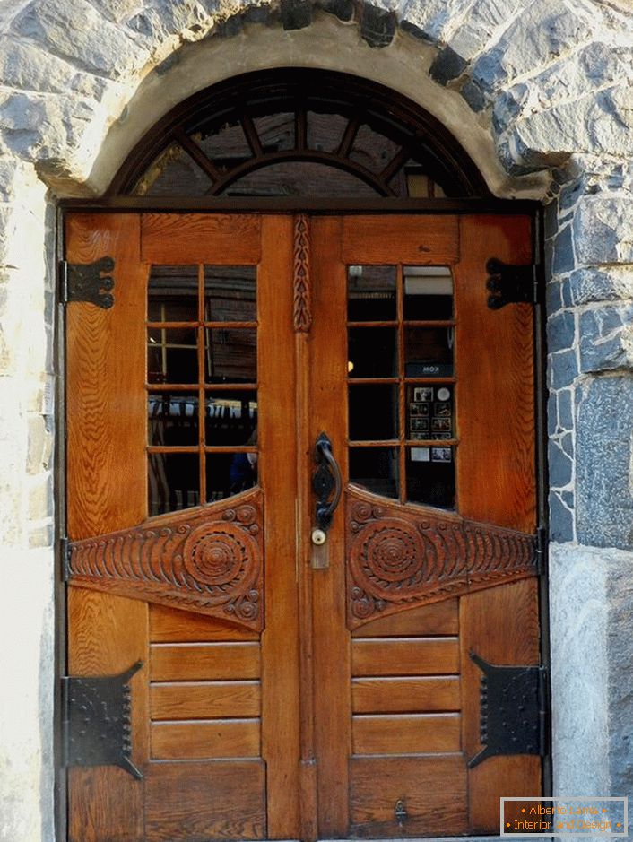 A szecessziós stílusú ajtók díszítik egy természetes kőburkolatú homlokzat ház ajtaját. 