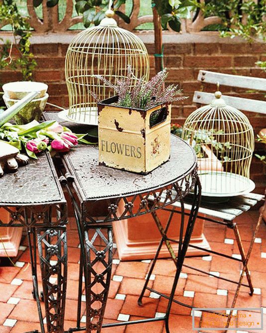 Kovácsolt asztal, dobozok virágokkal és ketrecekkel madarak számára