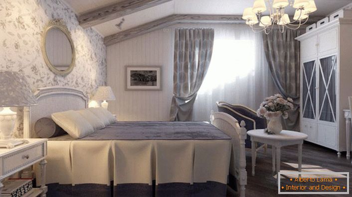 Az ország stílusában lévő hálószoba csendes kék árnyalatú. Az ágy fején lévő fal egy virágos mintával borított tapéta.